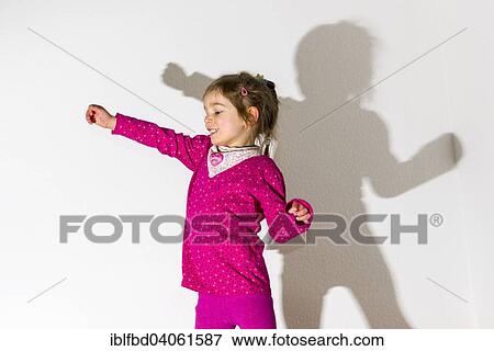 "Girl, 3 years, wearing a pink shirt, dancing, casting a shadow on a white wall" View Large Photo Image Stock Photo - "Girl, 3 years, wearing a pink shirt, dancing, casting a shadow on a white wall". Fotosearch