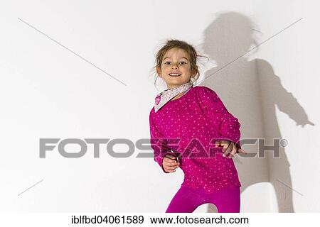 "Girl, 3 years, wearing a pink shirt, dancing, casting a shadow on a white wall" View Large Photo Image Stock Photo - "Girl, 3 years, wearing a pink shirt, dancing, casting a shadow on a white wall". Fotosearch