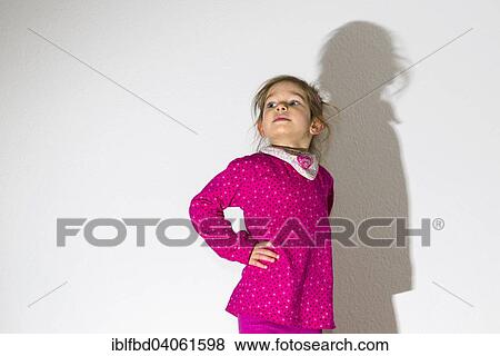 "Girl, 3 years, wearing a pink shirt, looking arrogant, casting a shadow on a white wall" View Large Photo Image Stock Photo - "Girl, 3 years, wearing a pink shirt, looking arrogant, casting a shadow on a white wall". Fotosearch