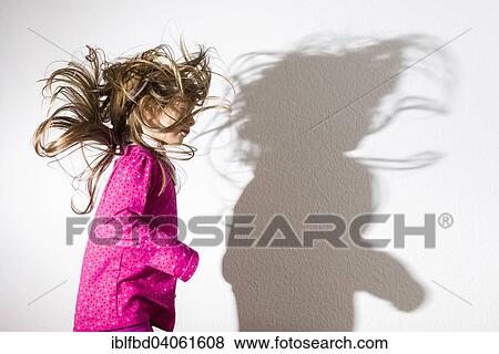 Stock Photo - "Girl, 3 years, wearing a pink shirt, dancing, casting a shadow on a white wall". Fotosearch