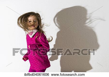 "Girl, 3 years, wearing a pink shirt, dancing, casting a shadow on a white wall" View Large Photo Image Stock Photograph - "Girl, 3 years, wearing a pink shirt, dancing, casting a shadow on a white wall". Fotosearch