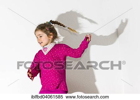 "Girl, 3 years, wearing a pink shirt, dancing, casting a shadow on a white wall" View Large Photo Image Stock Photography - "Girl, 3 years, wearing a pink shirt, dancing, casting a shadow on a white wall". Fotosearch