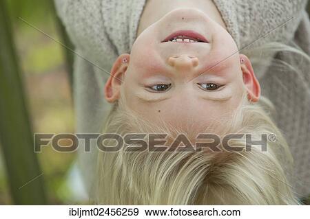 Stock Photo - "Girl, 4 years old, hanging on to a wooden fence, upside down". Fotosearch