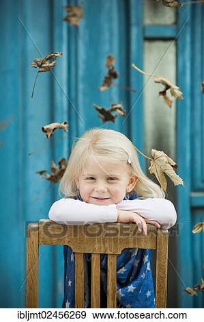 Stock Photo - "Girl, 4 years old leaning on a chair, leaves falling". Fotosearch