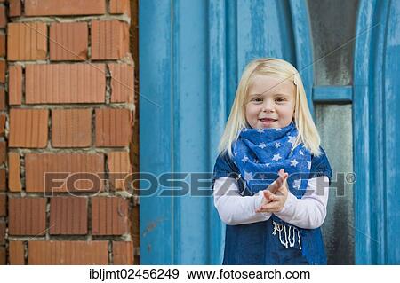 Stock Photo - "Girl, 4 years old, standing in front of a blue door". Fotosearch