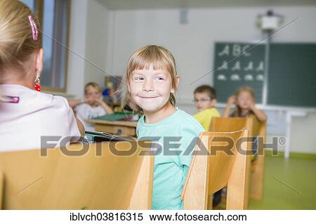 "Girl, 6, sitting at a school desk and turning to look behind, in Reith im Alpbachtal, Kufstein District, Tyrol, Austria, Europe" View Large Photo Image Stock Photography - "Girl, 6, sitting at a school desk and turning to look behind, in Reith im Alpbachtal, Kufstein District, Tyrol, Austria, Europe". Fotosearch
