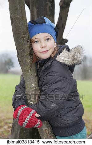 Stock Photography - "Girl, 9, wearing a hat and gloves, on a tree". Fotosearch