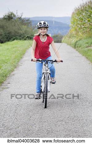 "Girl, 9 years, riding a bicycle wearing a helmet" View Large Photo Image Stock Photo - "Girl, 9 years, riding a bicycle wearing a helmet". Fotosearch