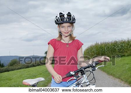 "Girl, 9 years, wearing a bicycle helmet, standing next to her bike" View Large Photo Image Stock Photo - "Girl, 9 years, wearing a bicycle helmet, standing next to her bike". Fotosearch