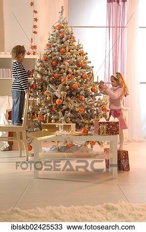 Girl and boy decorating a Christmas tree View Large Photo Image Stock Image - Girl and boy decorating a Christmas tree. Fotosearch
