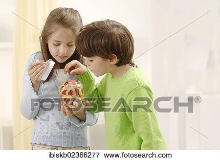 Stock Photo - Girl and boy nibbling on Christmas cookies. Fotosearch
