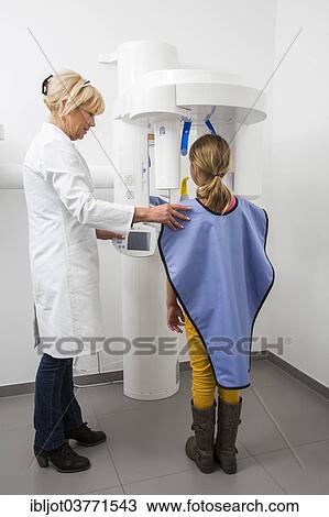 Stock Image - "Girl being prepared for an x-ray of her teeth, wearing a lead vest as radiation protection, Germany, Europe". Fotosearch