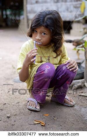Stock Photo - "Girl brushing her teeth outside a house, Lompong Commune, Bathi District, Takeo Province, Cambodia, Asia". Fotosearch