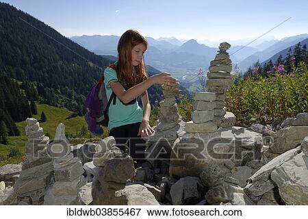 "Girl building cairns while mountain climbing, on the Austrian route to Purtscheller House on Hohen Goll Mountain, with a view over the Salzach Valley, Berchtesgaden Land district, Upper Bavaria, Bavaria, Germany, Europe" View Large Photo Image Stock Photo - "Girl building cairns while mountain climbing, on the Austrian route to Purtscheller House on Hohen Goll Mountain, with a view over the Salzach Valley, Berchtesgaden Land district, Upper Bavaria, Bavaria, Germany, Europe". Fotosearch
