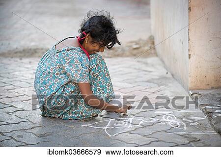 "Girl creating a traditional Rangoli, Kolam or Muggu, decorative pattern made of coloured sand, outside a door, Rameswaram, Pamban Island, Tamil Nadu, India, Asia" View Large Photo Image Stock Photo - "Girl creating a traditional Rangoli, Kolam or Muggu, decorative pattern made of coloured sand, outside a door, Rameswaram, Pamban Island, Tamil Nadu, India, Asia". Fotosearch