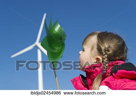 Girl holding a small pinwheel in front of a large wind turbine View Large Photo Image Stock Photograph - Girl holding a small pinwheel in front of a large wind turbine. Fotosearch