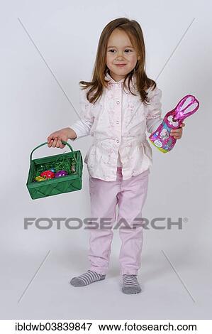 Girl holding an Easter basket and a chocolate Easter bunny View Large Photo Image Stock Photo - Girl holding an Easter basket and a chocolate Easter bunny. Fotosearch