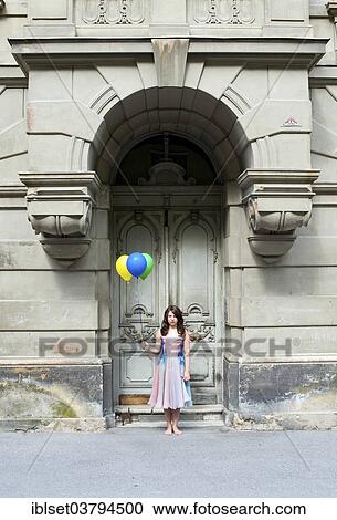 Girl holding balloons in front of an old door View Large Photo Image Stock Image - Girl holding balloons in front of an old door. Fotosearch