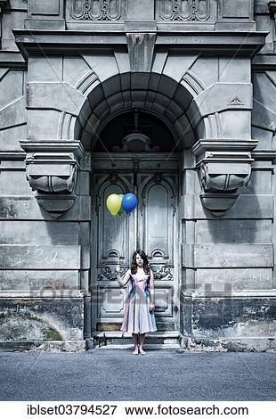 Girl holding balloons in front of an old door View Large Photo Image Stock Photo - Girl holding balloons in front of an old door. Fotosearch