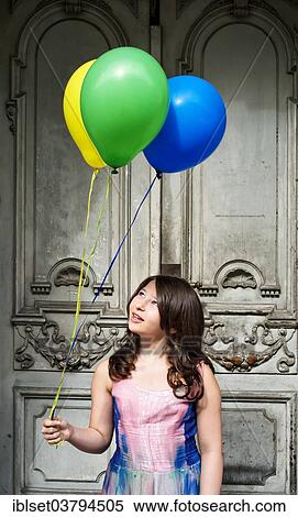Girl holding balloons in front of an old door View Large Photo Image Stock Photography - Girl holding balloons in front of an old door. Fotosearch