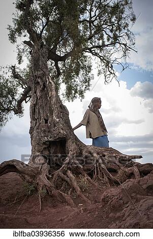Stock Photograph - "Girl in front of an ancient trees, Lalibela, Ethiopia, Africa". Fotosearch
