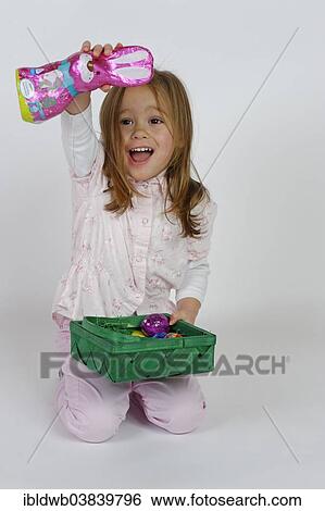 Girl is happy about an Easter basket and a chocolate Easter bunny View Large Photo Image Stock Photograph - Girl is happy about an Easter basket and a chocolate Easter bunny. Fotosearch