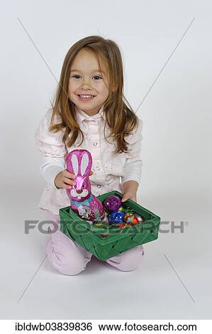 Girl is happy about an Easter basket and a chocolate Easter bunny View Large Photo Image Stock Photograph - Girl is happy about an Easter basket and a chocolate Easter bunny. Fotosearch