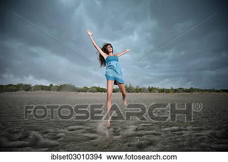 Picture - "Girl jumping on a beach, rain clouds, Cavallino, Jesolo, Venedig, Italy, Europe". Fotosearch