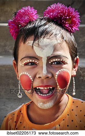 Stock Image - "Girl, laughing, with flowers in her hair, her face is painted with Thanaka cream, Bagan, Burma, Myanmar, Southeast Asia, Asia". Fotosearch