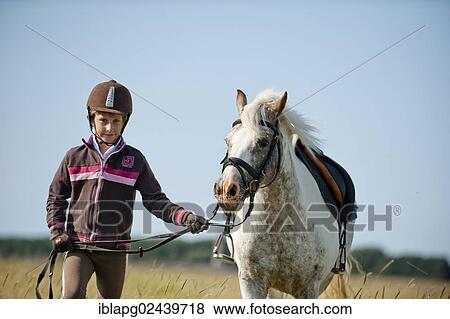 Girl leading a pony on the reins View Large Photo Image Stock Photo - Girl leading a pony on the reins. Fotosearch