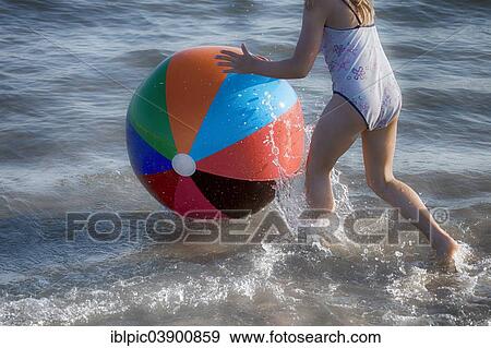 Girl playing with a colourful beach ball in the sea View Large Photo Image Stock Photo - Girl playing with a colourful beach ball in the sea. Fotosearch