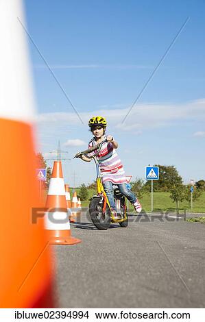 Girl practicing to ride slalom on a scooter at a traffic awareness course View Large Photo Image Picture - Girl practicing to ride slalom on a scooter at a traffic awareness course. Fotosearch