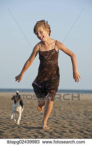 Stock Image - Girl running with a Dansk-Svensk Gardshund or Danish-Swedish Farmdog on the beach. Fotosearch