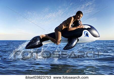 "Girl sitting on an inflatable orca jumping out of the water, composite image" View Large Photo Image Stock Image - "Girl sitting on an inflatable orca jumping out of the water, composite image". Fotosearch