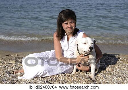 Girl sitting on the beach with a Staffordshire Bull Terrier View Large Photo Image Picture - Girl sitting on the beach with a Staffordshire Bull Terrier. Fotosearch