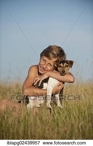 Stock Photo - Girl sitting with a Dansk-Svensk Gardshund or Danish Swedish Farmdog in a meadow. Fotosearch