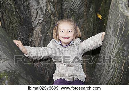 "Girl, six years, sitting on a tree" View Large Photo Image Stock Photo - "Girl, six years, sitting on a tree". Fotosearch