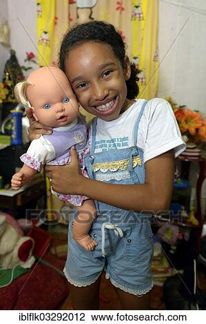 "Girl, smiling, holding a doll in an apartment in a slum or favela, Jacarezinho favela, Rio de Janeiro, Rio de Janeiro State, Brazil, South America" View Large Photo Image Stock Image - "Girl, smiling, holding a doll in an apartment in a slum or favela, Jacarezinho favela, Rio de Janeiro, Rio de Janeiro State, Brazil, South America". Fotosearch
