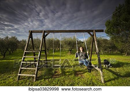 "Girl swinging on a wooden swing in front of an olive grove, Tuscany, Italy, Europe" View Large Photo Image Stock Photo - "Girl swinging on a wooden swing in front of an olive grove, Tuscany, Italy, Europe". Fotosearch