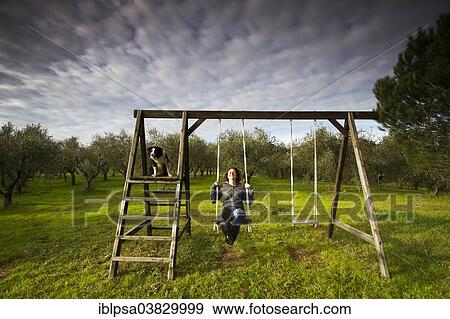 "Girl swinging on a wooden swing in front of an olive grove, Tuscany, Italy, Europe" View Large Photo Image Stock Photo - "Girl swinging on a wooden swing in front of an olive grove, Tuscany, Italy, Europe". Fotosearch