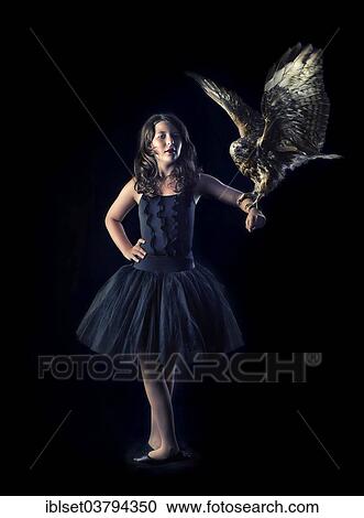 Stock Image - Girl wearing a black ballet dress with a bird of prey on her arm. Fotosearch