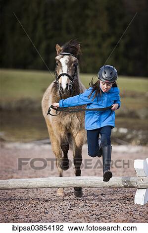 "Girl wearing a riding helmet jumping over an obstacle with a pony, Falbe, with bridle, Tyrol, Austria, Europe" View Large Photo Image Stock Image - "Girl wearing a riding helmet jumping over an obstacle with a pony, Falbe, with bridle, Tyrol, Austria, Europe". Fotosearch
