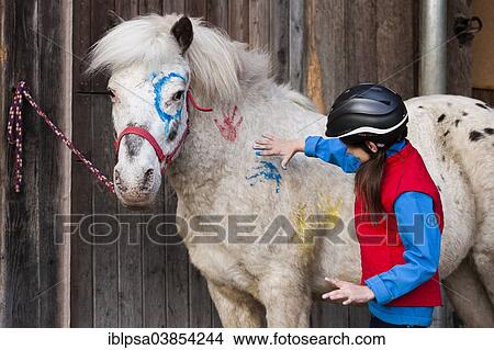 "Girl wearing a riding helmet painting a pony with finger paints, gray, Tyrol, Austria, Europe" View Large Photo Image Picture - "Girl wearing a riding helmet painting a pony with finger paints, gray, Tyrol, Austria, Europe". Fotosearch