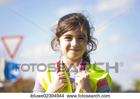 Girl wearing a safety vest in front of a road sign View Large Photo Image Picture - Girl wearing a safety vest in front of a road sign. Fotosearch