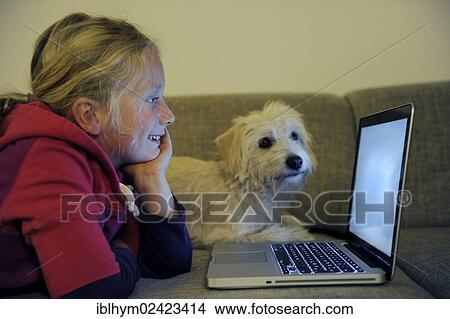 Girl with a dog at the computer on the sofa View Large Photo Image Picture - Girl with a dog at the computer on the sofa. Fotosearch