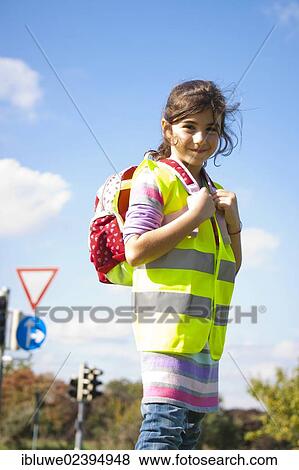 Girl with a school bag wearing a safety vest in front of a road sign View Large Photo Image Stock Photo - Girl with a school bag wearing a safety vest in front of a road sign. Fotosearch