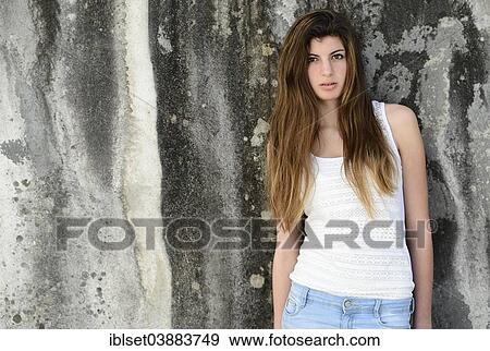 Stock Photo - "Girl with long hair, 15 years, standing in front of an old weathered wall". Fotosearch