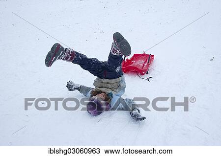 Stock Image - "Girls rolling in the snow while sledding, Sonnenberg, St. Andreasberg, Lower Saxony, Germany, Europe". Fotosearch