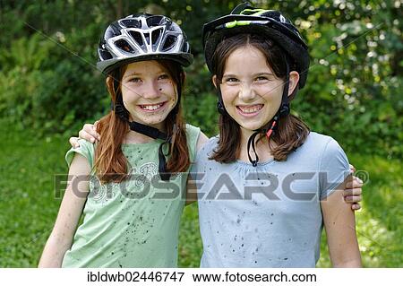 Stock Photo - "Girls wearing cycle helmets, clotted with mud after a mountain bike tour". Fotosearch