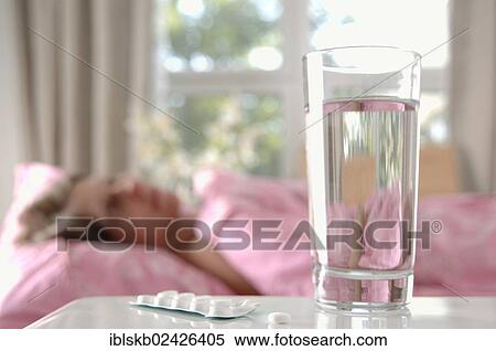 "Glass of water with tablets, woman lying in bed at back" View Large Photo Image Stock Photography - "Glass of water with tablets, woman lying in bed at back". Fotosearch